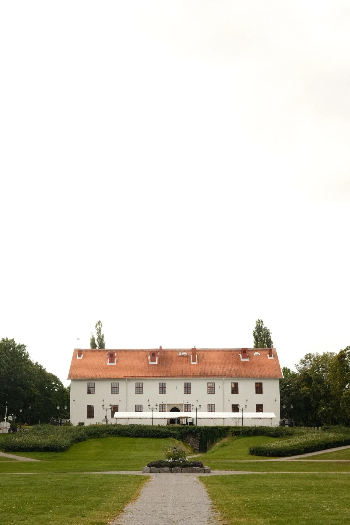 Den vita herrgården med rött tegeltak, sedd över parken