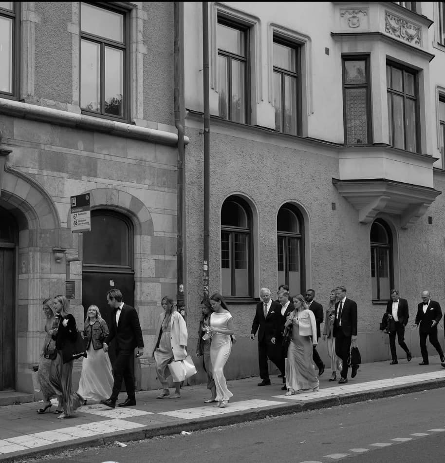 Bröllopssällskapet går längs en gata i Stockholm, i svartvitt