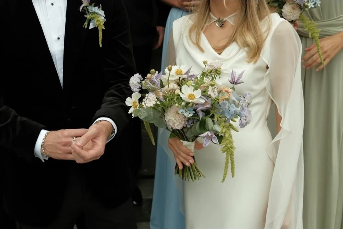 Brudgummen och bruden med sin brudbukett av sommarblommor
